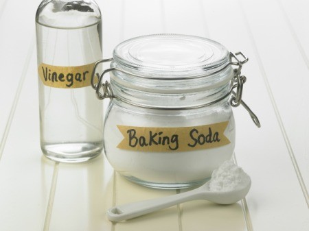 Glass bottle of Vinegar next to a jar of baking soda.