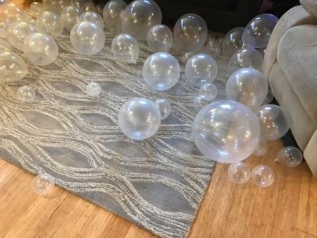 Clear balloons in three sizes on a floor.