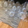 Clear balloons in three sizes on a floor.