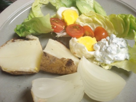 Plate with cooked potato, egg, dressing and lettuce