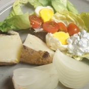 Plate with cooked potato, egg, dressing and lettuce