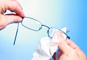 Person cleaning eyeglass lenses with a cloth.