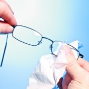 Person cleaning eyeglass lenses with a cloth.
