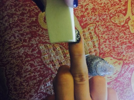 Placing nail polish covered sponge on nail.