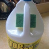 A sponge stored in the handle of a bottle of cleaner.