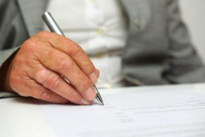 Older man signing a legal document.