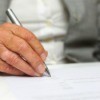 Older man signing a legal document.