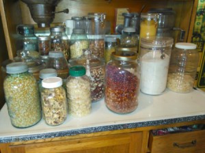 A counter filled with pickle jars with beans, rice or other dry goods stored in them.