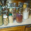 A counter filled with pickle jars with beans, rice or other dry goods stored in them.