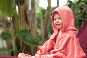 Happy Toddler wearing a pink hooded blanket outside.