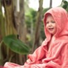 Happy Toddler wearing a pink hooded blanket outside.