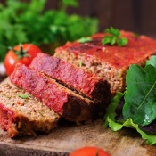 Vegetable meatloaf cut into slices surrounded by greens.