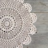 Beautiful intricate crochet doily on a grey wood background.