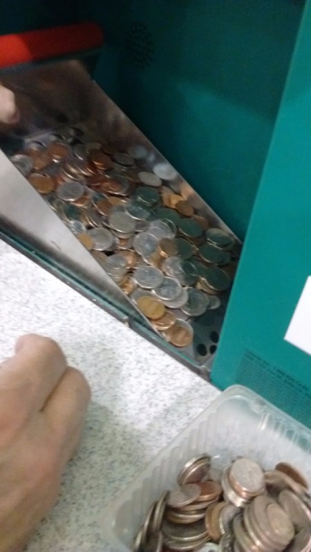 Coins being fed into the hopper of the Coinstar machine.