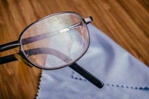 A pair of scratched eyeglasses on a cleaning cloth.