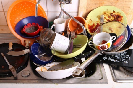 A sink full of dirty dishes, including plates and a frying pan.