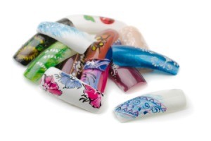 Pile of artificial nails with nail art designs painted on them.