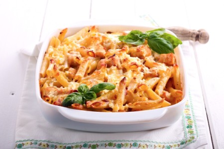 Baked Chicken Penne in a white dish with sprigs of fresh basil.