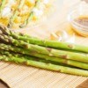 Asparagus in front of a penne dish and a sauce.