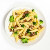A plate of penne with sausage and broccoli.