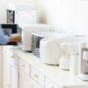 A white kitchen counter filled with small white appliances in a row.