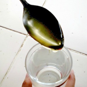 A spoonful of honey being added to water.
