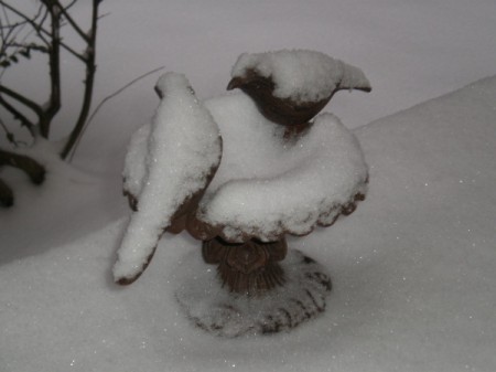 A birdbath with concrete birds covered in snow.