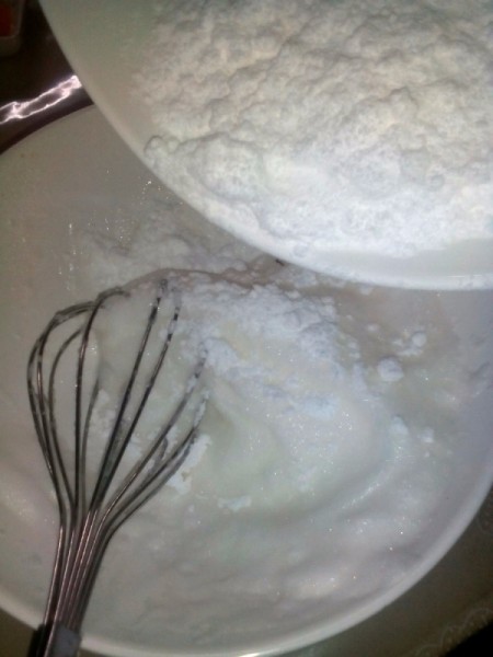 adding powdered sugar to whipped egg white