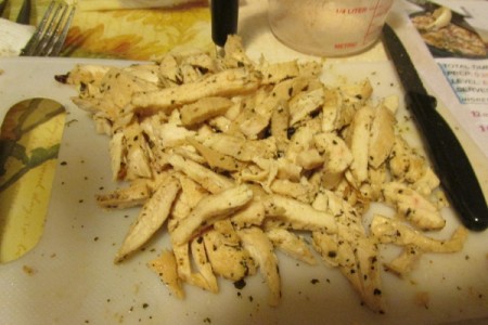 Chopped cooked, seasoned chicken on cutting board