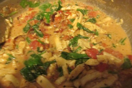 Chicken, spinach, bacon and herbs cooking in pan.