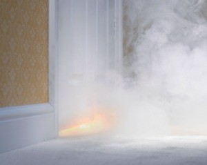 Smoke from a house fire coming from under a door.
