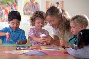 Kids working on a Sunday school craft with a teacher.