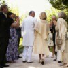 An older couple walking down the center aisle during an outdoor wedding ceremony.
