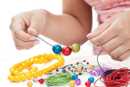 A girl making a beaded bracelet with colorful beads.