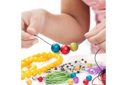A girl making a beaded bracelet with colorful beads.
