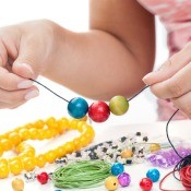 A girl making a beaded bracelet with colorful beads.