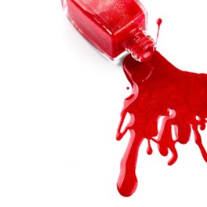 A bottle of nail polish spilled on a white background.