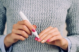 A woman in a grey sweater doing a manicure on herself.