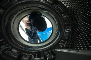 A front loading washing machine, with a person adding clothes.