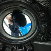 A front loading washing machine, with a person adding clothes.