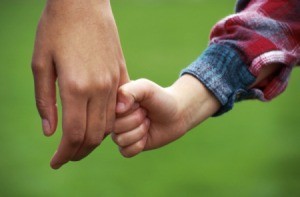 A child holding hands with a young adult.