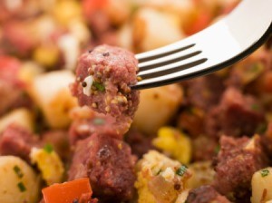 A fork with some corned beef hash over a plate.