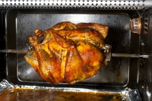 A chicken being cooked in a home rotisserie.