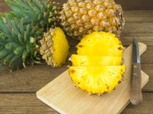 A fresh pineapple being chopped up for use in a recipe.