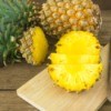 A fresh pineapple being chopped up for use in a recipe.