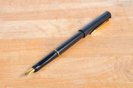A fountain pen on a wood surface.