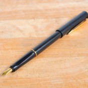 A fountain pen on a wood surface.