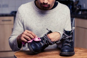 A man cleaning his leather work boots with a cloth.