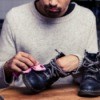 A man cleaning his leather work boots with a cloth.