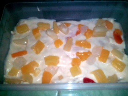 Adding fruit cocktail to the top of pudding.